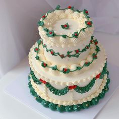 a three tiered cake with holly decorations on it