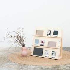 a vase with some branches in it next to a book shelf on a table top