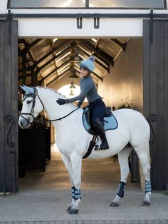 a woman riding on the back of a white horse in front of an open doorway