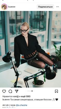 a woman sitting on top of a desk in front of a window wearing black stockings