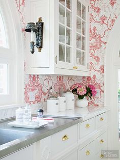 a kitchen with white cabinets and pink wallpaper