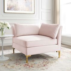 a living room with a pink chair and white vase on the floor next to a window