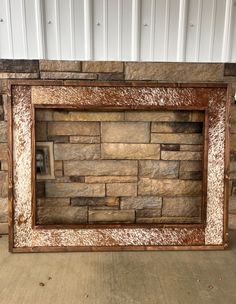 a stone fireplace with a wooden frame on the front and back sides, sitting against a white wall