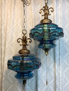 two blue glass lamps hanging from a ceiling