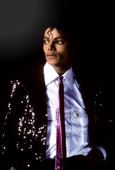 a man in a white shirt and purple tie with sequins on his jacket