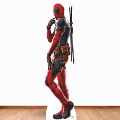 a statue of deadpool is standing on a wooden floor in front of a white wall