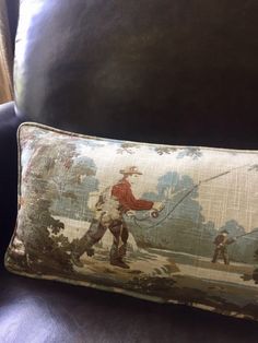 a pillow that is sitting on top of a leather chair with a fishing scene on it