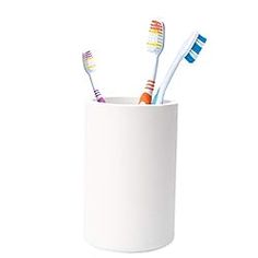 three toothbrushes in a white cup on a white background with clippings