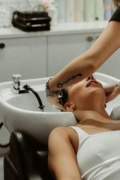 a woman getting her hair washed in a sink at the barber's counter top