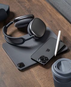 an iphone, headphones and cup on a table