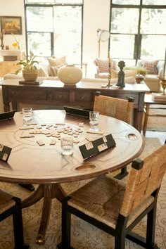 a round table with chairs around it in a living room filled with couches and windows