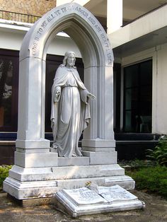 a statue in front of a building with a cross on the ground next to it