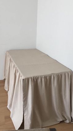 an empty room with a table and rug on the floor in front of a white wall