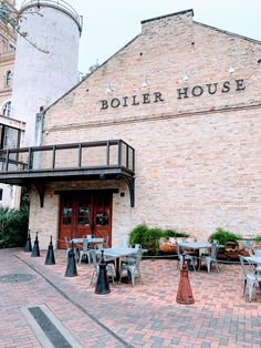 an outdoor restaurant with tables and umbrellas on the patio area next to a brick building