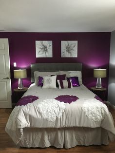 a bedroom with purple and white decor on the walls, bed in front of two nightstands