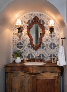 a bathroom with a sink, mirror and lights on the wall above it's cabinet