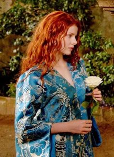 a woman with red hair holding a white rose