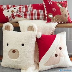 four pillows with teddy bears on them sitting on a bench in front of a wall