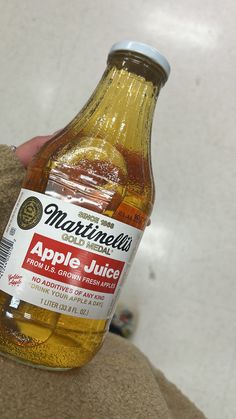 a bottle of apple juice being held by someone