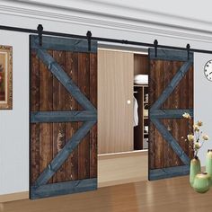 an open barn door with two vases and flowers on the table in front of it