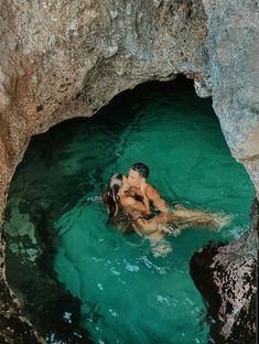 a man swimming in the water next to a cave