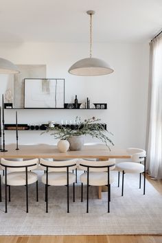 the dining room table is surrounded by white chairs