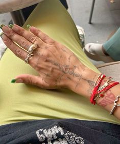 a woman's hand with writing on it and four rings around her wrist, sitting in an office chair