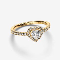 Radiate love in our Elevated Heart Ring featuring a symbolic heart-shaped clear cubic zirconia, set in a 14k gold plating with a pavé halo. Its raised stone and claw setting highlight the eye-catching centre, while half of the ring shank is adorned with pavé. Perfect for adding a touch of love to any outfit, this ring captures the essence of heartfelt connections. - Pandora Elevated Heart Ring - 14k Gold-plated unique metal blend / Cubic Zirconia / Clear - Sz. 7.5 Promise Ring Pandora Gold, Unique Promise Rings For Her Gold, Pandora Gold Heart Ring, Pandora Gold Jewelry, Gold Pandora Ring, Pandora Gold Rings, Promise Rings For Her Gold, Gold Promise Rings For Her, Pandora Elevated Heart Ring