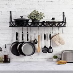 pots and pans are hanging on the wall in this kitchen with white brick walls