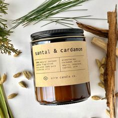 a jar of candle sitting on top of a table next to some leaves and branches