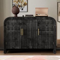 a black and gold sideboard in a living room with pictures on the wall behind it