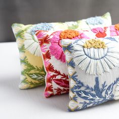 three decorative pillows on a white surface