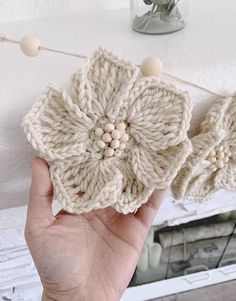 a hand is holding two crocheted coasters in front of a white fireplace