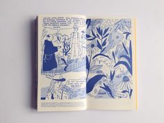 an open book with blue ink on the pages and illustrations in it, sitting on a white surface