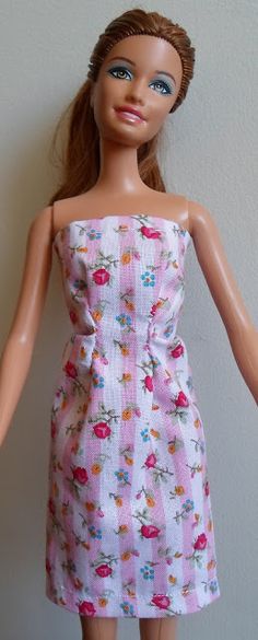 a doll wearing a dress with flowers on it's chest and arms, standing next to a wall