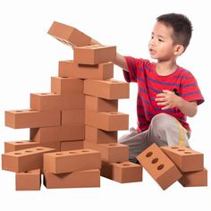 a young boy is playing with cardboard blocks