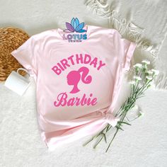 a pink shirt with the words birthday barbie on it next to flowers and a wicker basket