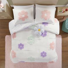 a white bed with pink and purple flowers on it