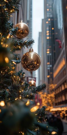 a christmas tree with ornaments hanging from it's branches in front of tall buildings