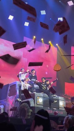 a group of people standing on top of a truck in front of a stage with lots of lights