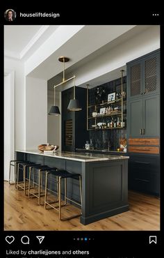 an image of a kitchen with black cabinets and bar stools in the center area