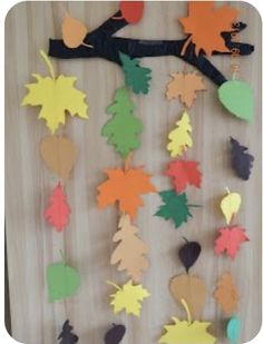 the fall leaves are cut out from paper and hung on a tree branch with scissors