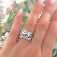 a woman's hand with a diamond ring on it and flowers in the background