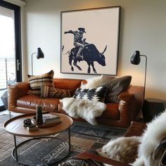 a living room filled with furniture and a cowgirl painting on the wall above it