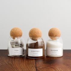 three glass jars filled with spices on top of a wooden table