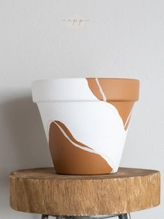 two white and brown flower pots sitting on top of a wooden table next to each other