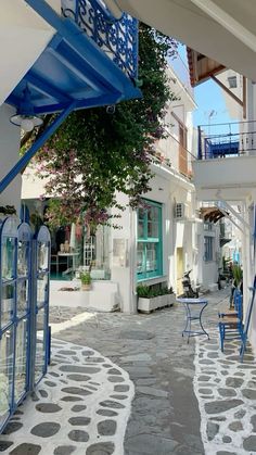 an alley way with tables and chairs on the side, in front of a building