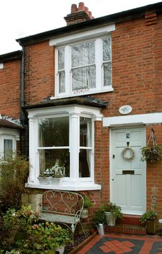 an image of a brick house with white trim and windows on the front, and a bench next to it