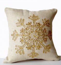 a white pillow with gold sequins and snowflakes on the front, sitting on a table