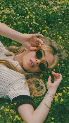 a woman laying in the grass with her eyes closed and sunglasses on top of her head